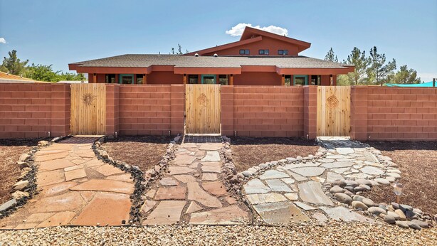 A modern building with a brick facade, a wooden gate, and a stone pathway leading to the entrance. - River Rock Studio w/private courtyard, 20 minutes to Zion (Virgin)