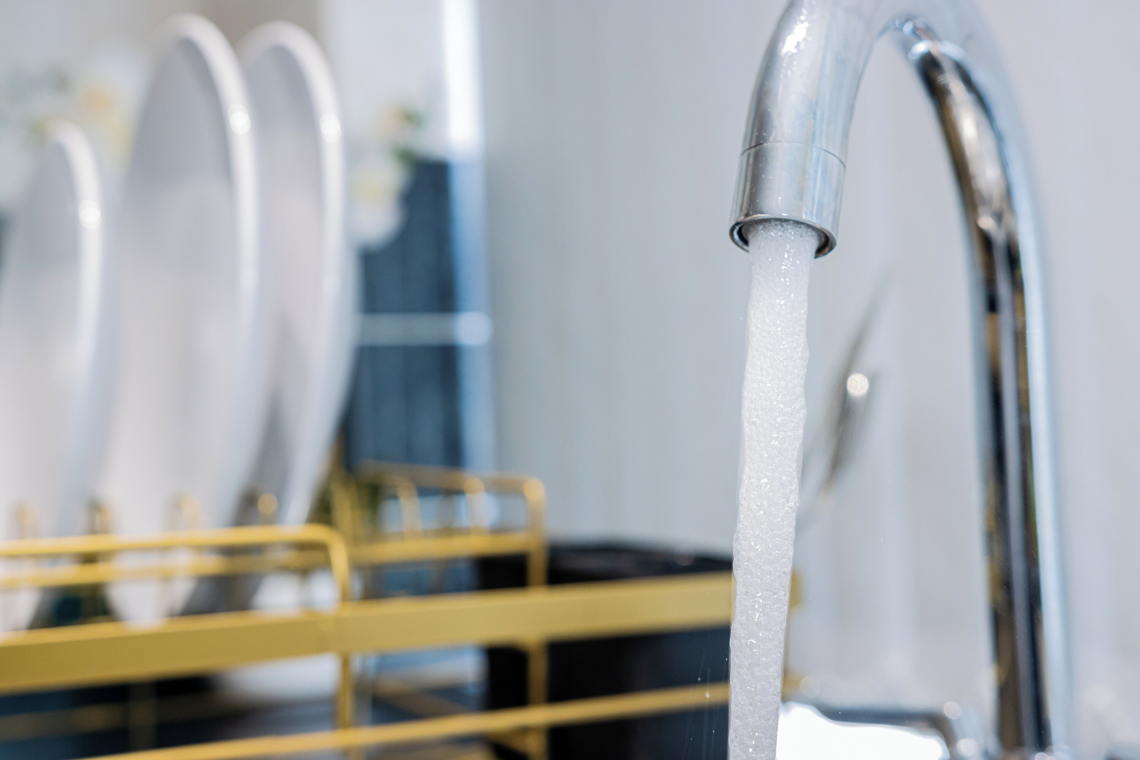 Gros plan d’un robinet moderne avec de l’eau qui coule, faisant partie d’une salle de bain.