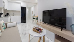 A modern living room with a flat-screen TV, a small round coffee table, and a sofa. - Apartment 2 bedrooms near Las Canteras beach (Las Palmas de Gran Canaria)