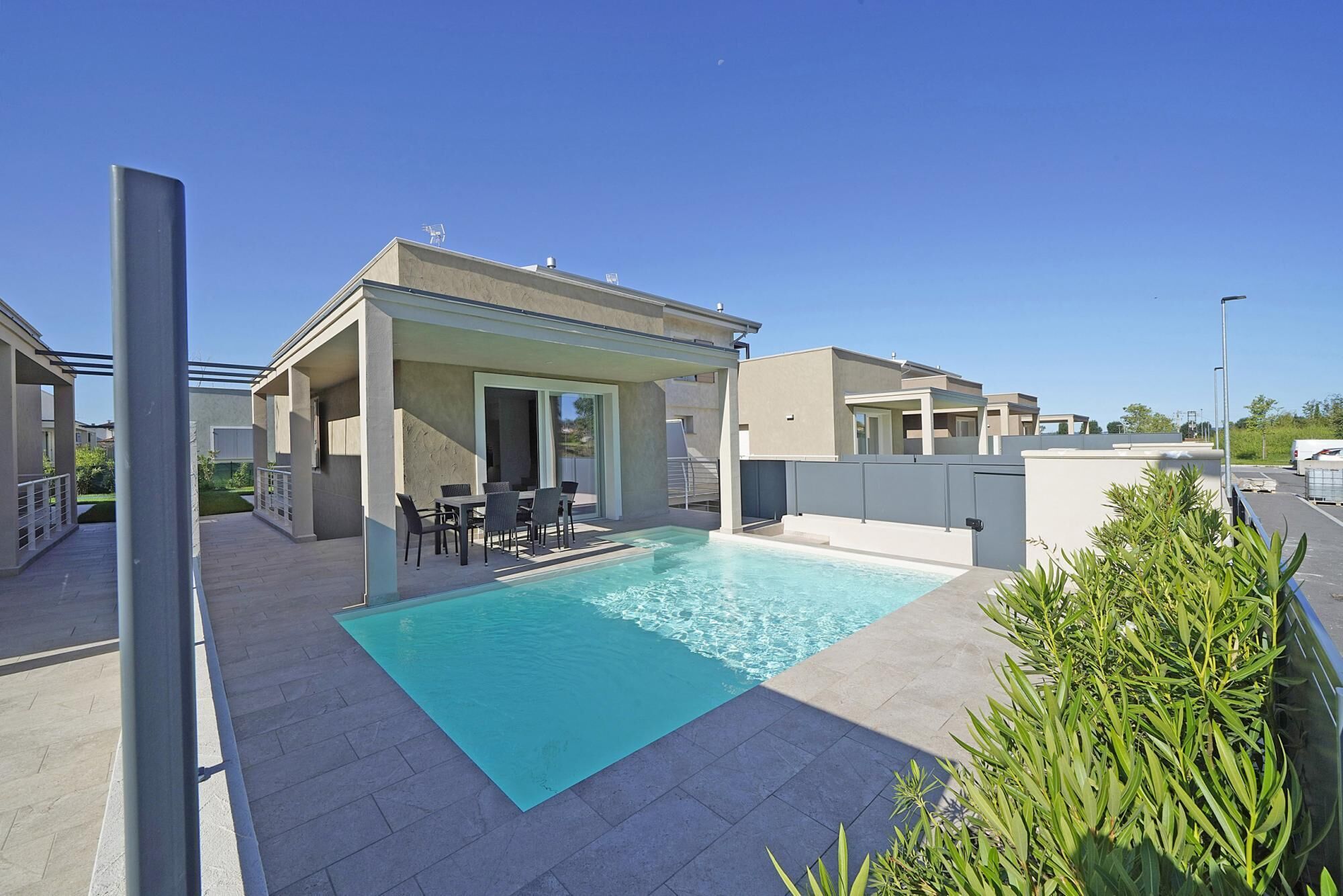 A modern outdoor pool area with a covered seating area and a clear blue pool.