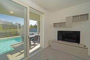 A modern living room with a TV, a pool, and a sliding glass door leading to an outdoor area.