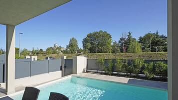 Relax by the pool surrounded by lush greenery and a serene hilly landscape.