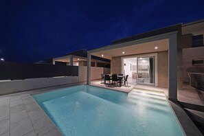 A modern outdoor pool area with a dining set and a covered patio. - Villa Prestige 17 by Wonderful Italy (Sirmione)