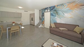 Ein modernes Wohnzimmer mit einer braunen Couch, einem Esstisch mit Stühlen und einer Küchenzeile mit Schränken und einem Herd.