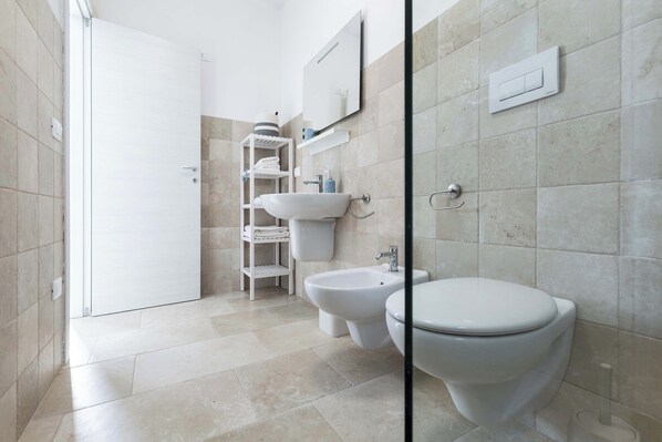 A modern bathroom with a toilet, bidet, and sink.