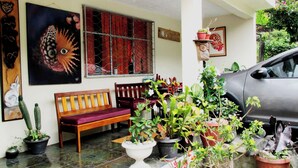 A covered porch with a wooden bench, potted plants, and a car parked outside. -  Athene Moon, ubicados en el barrio "San Vicente" diagonal a Refugio Spa (Baños de Agua Santa)
