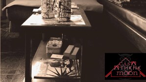 A room with a table displaying bottles, a bed, a couch, and a framed picture on the wall. -  Athene Moon, ubicados en el barrio "San Vicente" diagonal a Refugio Spa (Baños de Agua Santa)