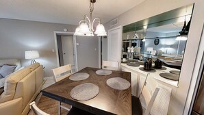 A dining area with a wooden table, four woven placemats, and a chandelier.
