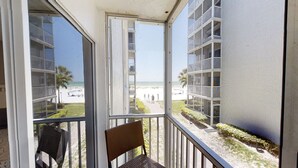 A balcony with a view of a beach and a building with multiple balconies.