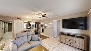 A living room with a grey sofa, a wooden entertainment unit, and a flat-screen TV.