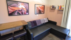 Un salon avec un canapé, une petite table et deux tableaux encadrés accrochés au mur.