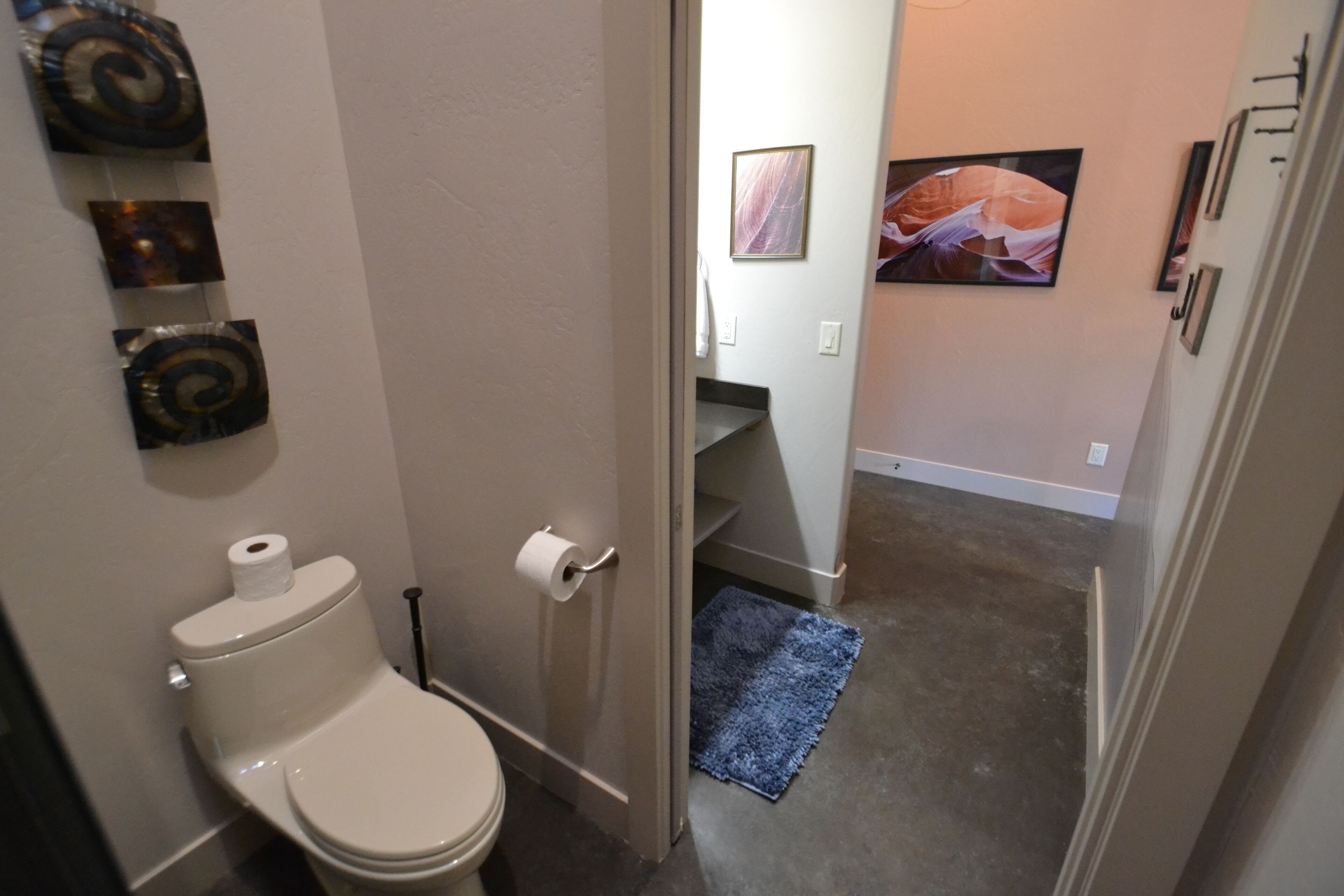 Une salle de bain avec des toilettes, un rouleau de papier toilette et un tapis bleu sur le sol.