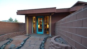 Un bâtiment moderne avec une porte bleue et un chemin de pierre menant à l’entrée.