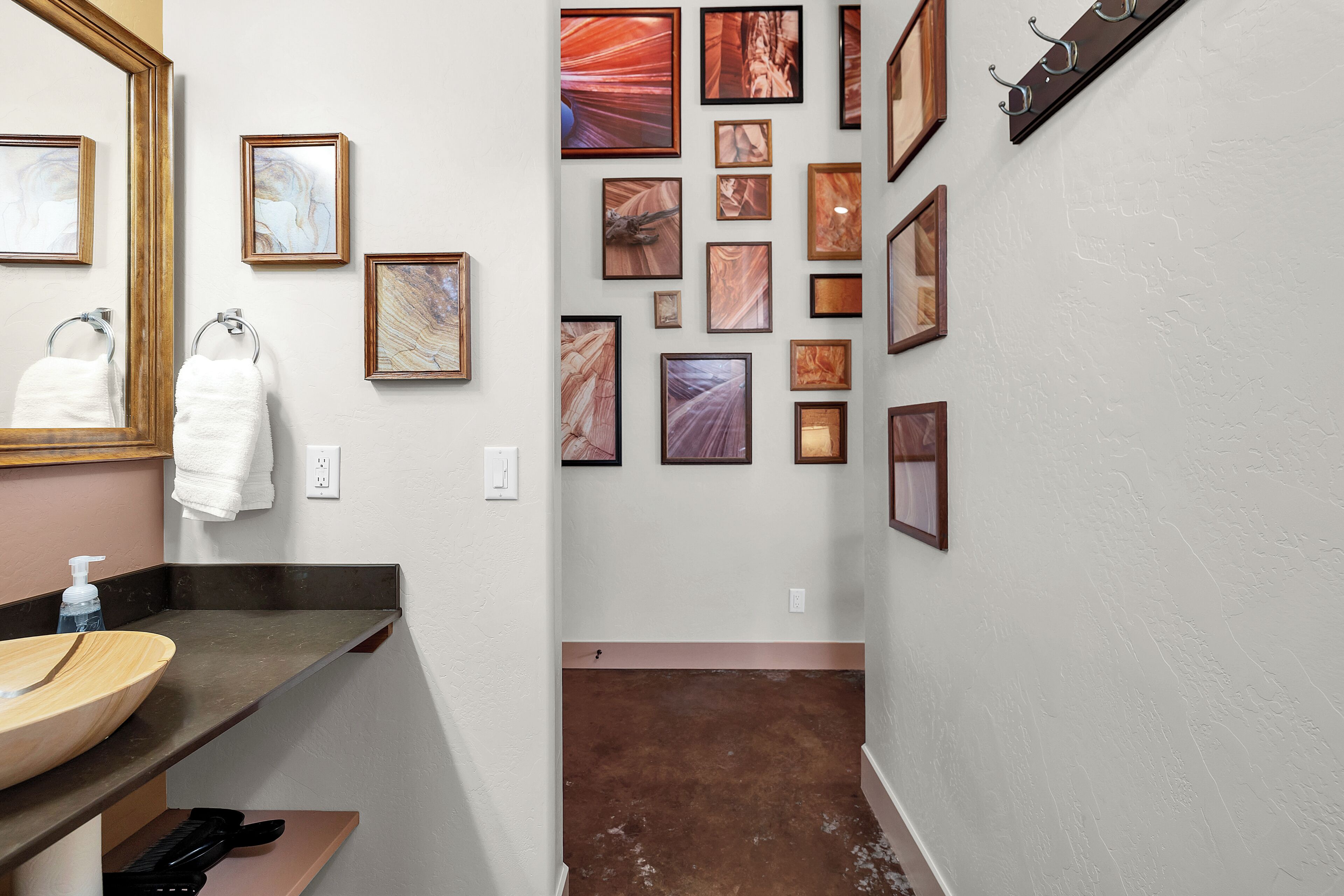 A bathroom with a wooden sink, towel rack, and framed artwork on the wall.