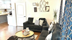 A living room with a dark grey sofa, a round coffee table, and a ceiling fan. - My house your house (Fort Smith)