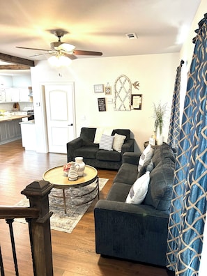 A living room with a dark grey sofa, a round coffee table, and a ceiling fan.