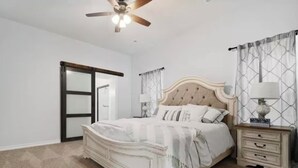 A bedroom with a bed, nightstands, a ceiling fan, and a door. - My house your house (Fort Smith)