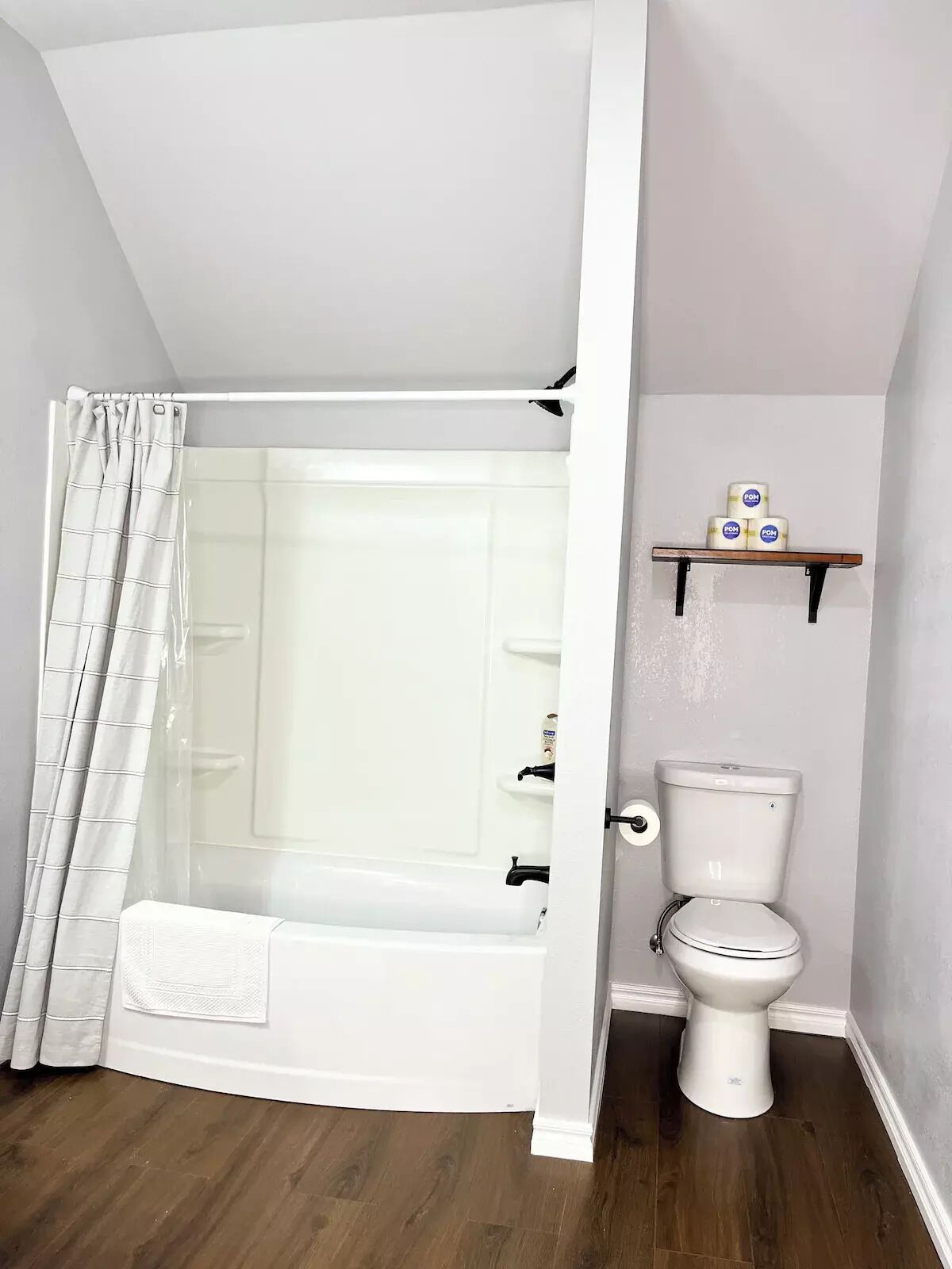 Ein Badezimmer mit Badewanne, Toilette und Ablage für Toilettenpapier.