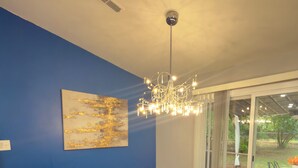 Ein stilvoller Essbereich mit Glastisch, schwarzen Stühlen, einer Chandelierleuchtre und einer blauen Akzentwand.