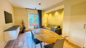 Una sala de estar moderna con una mesa de comedor de madera, un sofá y un televisor montado en la pared.