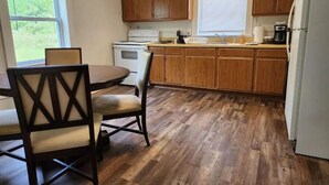 Une cuisine avec des meubles de rangement en bois, une cuisinière, un évier et une table à manger avec des chaises.