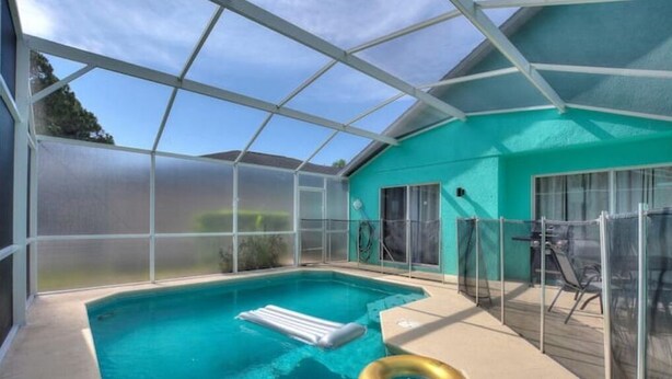 A covered swimming pool with a clear roof, a floating pool ladder, and a poolside table area. - Disney themed house with heated private pool. 15 minutes from Disney (Davenport)