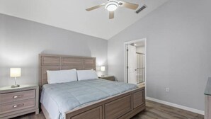 A bedroom with a bed, nightstands, a ceiling fan, and a door. - Disney themed house with heated private pool. 15 minutes from Disney (Davenport)