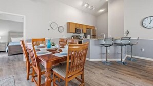 A modern kitchen with wooden cabinets, a microwave, and a sink. There is a dining area with a wooden table and chairs. - Disney themed house with heated private pool. 15 minutes from Disney (Davenport)