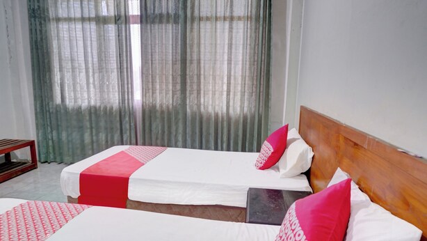 Habitación de hotel con dos camas, cada una con una colcha estampada en rojo y blanco, y almohadas a juego.