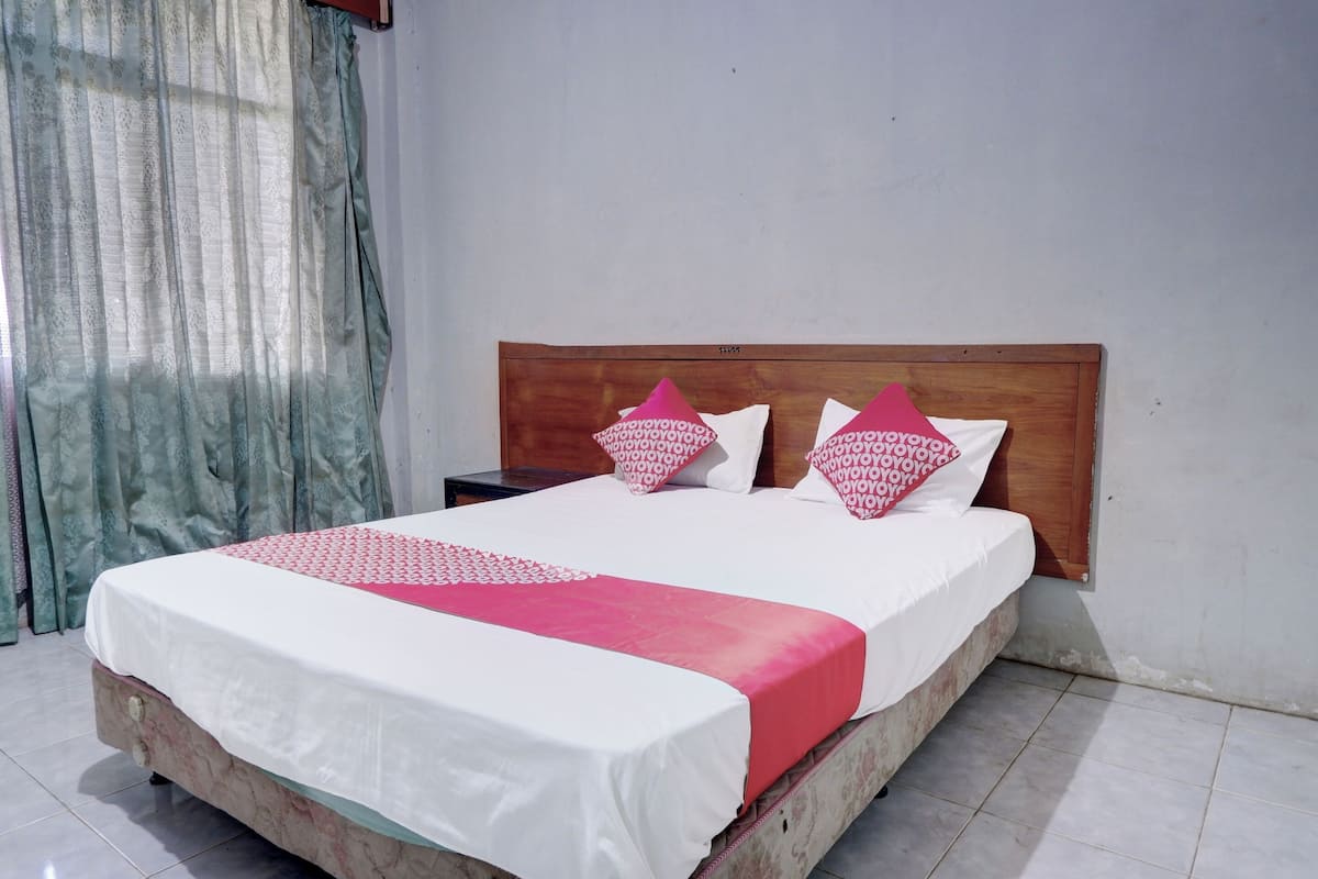 A bed with a wooden headboard, white bedding, and pink pillows.