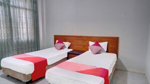 Dos camas individuales con cabeceros de madera, ropa de cama blanca y detalles en rojo.