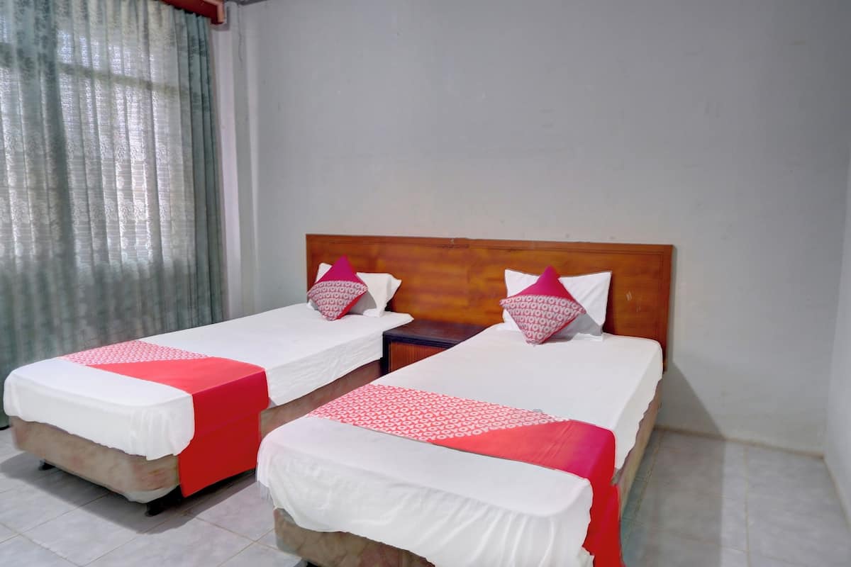 Two single beds with wooden headboards, white bedding, and red accents.
