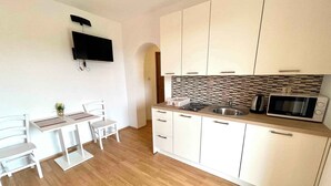 A small, modern kitchen with white cabinets, a wooden countertop, a built-in microwave, and a sink.
