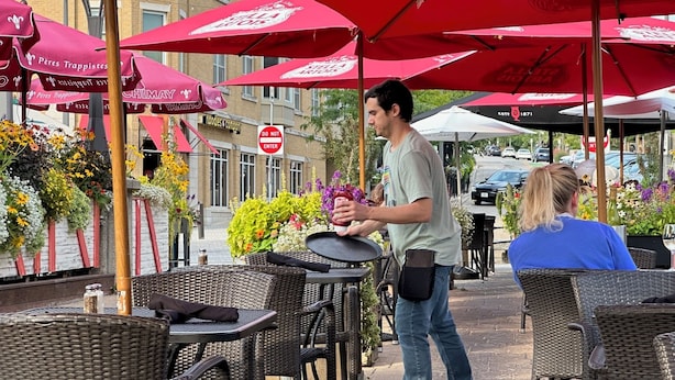 Outdoor seating with wicker chairs and red umbrellas, a 'DO NOT ENTER' sign, and a building with 'noodles & company' signage. - House in Quaint Neighborhood near Downtown Milwaukee Pet-Friendly! (Milwaukee)