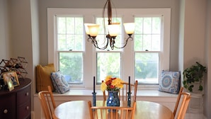 A dining area with a round table, wooden chairs, a chandelier, and a window seat with cushions. - House in Quaint Neighborhood near Downtown Milwaukee Pet-Friendly! (Milwaukee)