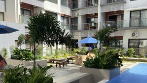 A modern apartment building with a rooftop pool area featuring outdoor seating and planters. - Modern Nearby Beach Apartment (Serrekunda)