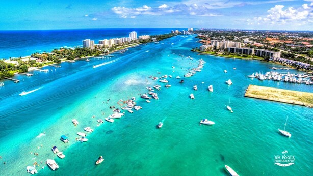 An aerial view of a coastal area with numerous boats, a marina, and buildings along the shore. - ON The Beach Juno! 4-Steps to the Beach! (Juno Beach)