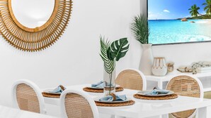 A dining area with a white table set for four, featuring woven placemats and wicker chairs. - ON The Beach Juno! 4-Steps to the Beach! (Juno Beach)