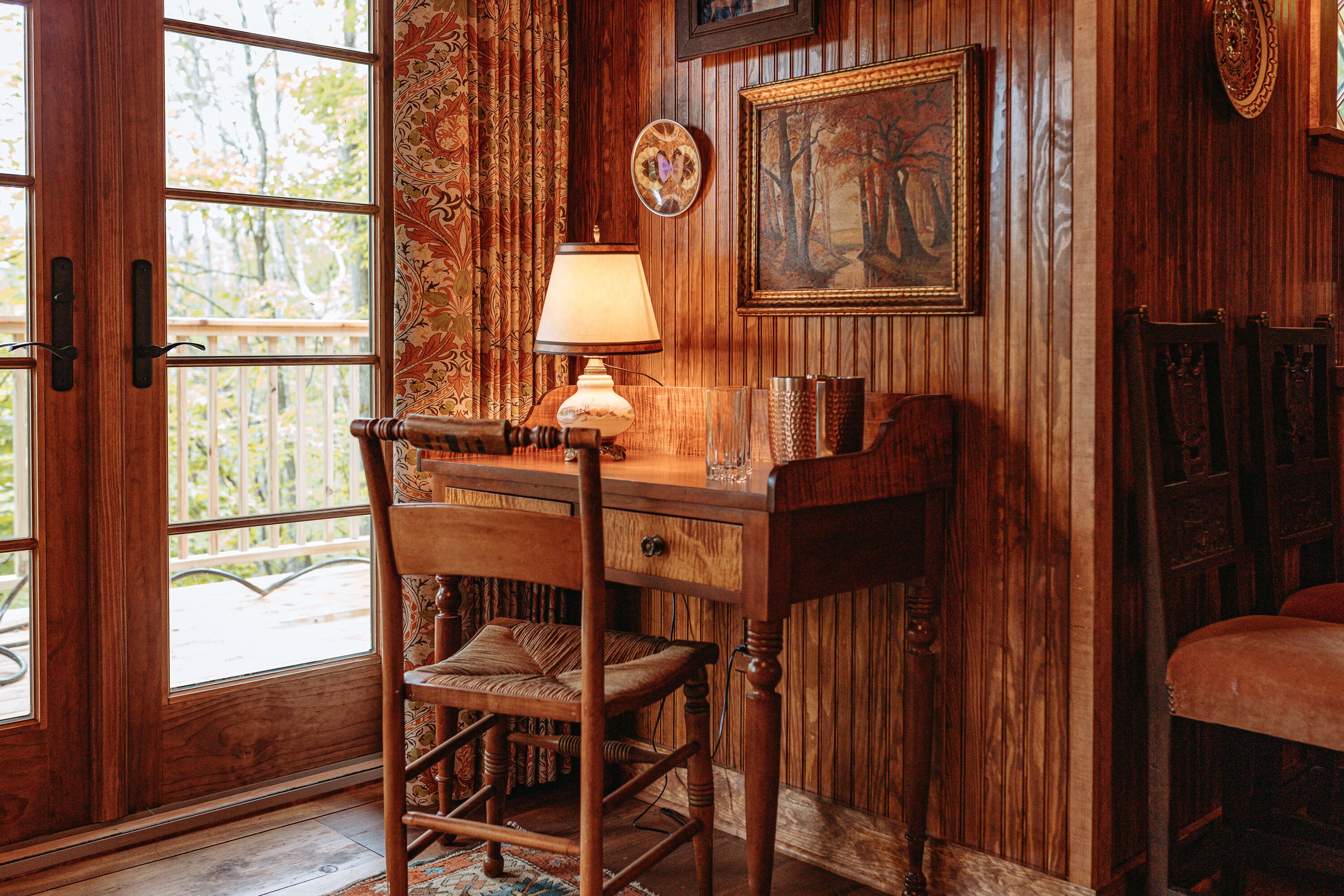 A wooden interior with a desk, chair, and a lamp.