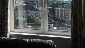 A room with a large window overlooking a cityscape, featuring buildings and a tower.