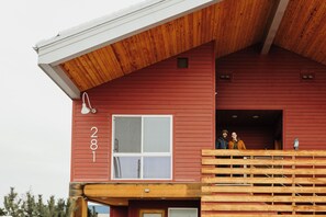 Un edificio rosso con il numero '281' sul lato, una finestra e una scala in legno che conduce a una zona coperta.