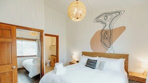 Et hotelværelse med en stor seng, et spejl, en lysekrone og et kunstværk på væggen.