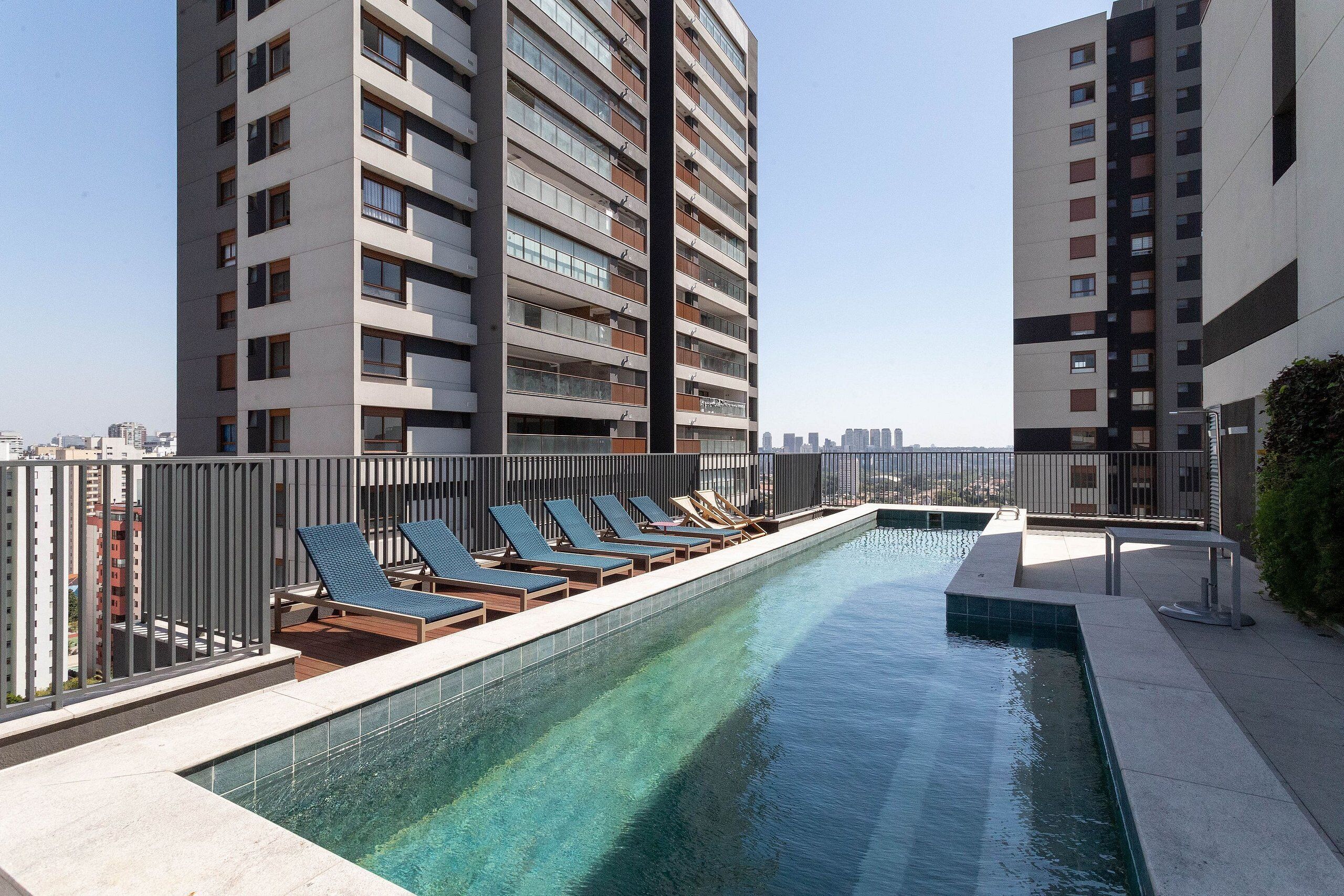 Une piscine sur le toit, dotée de chaises longues et offrant une vue sur les gratte-ciel.