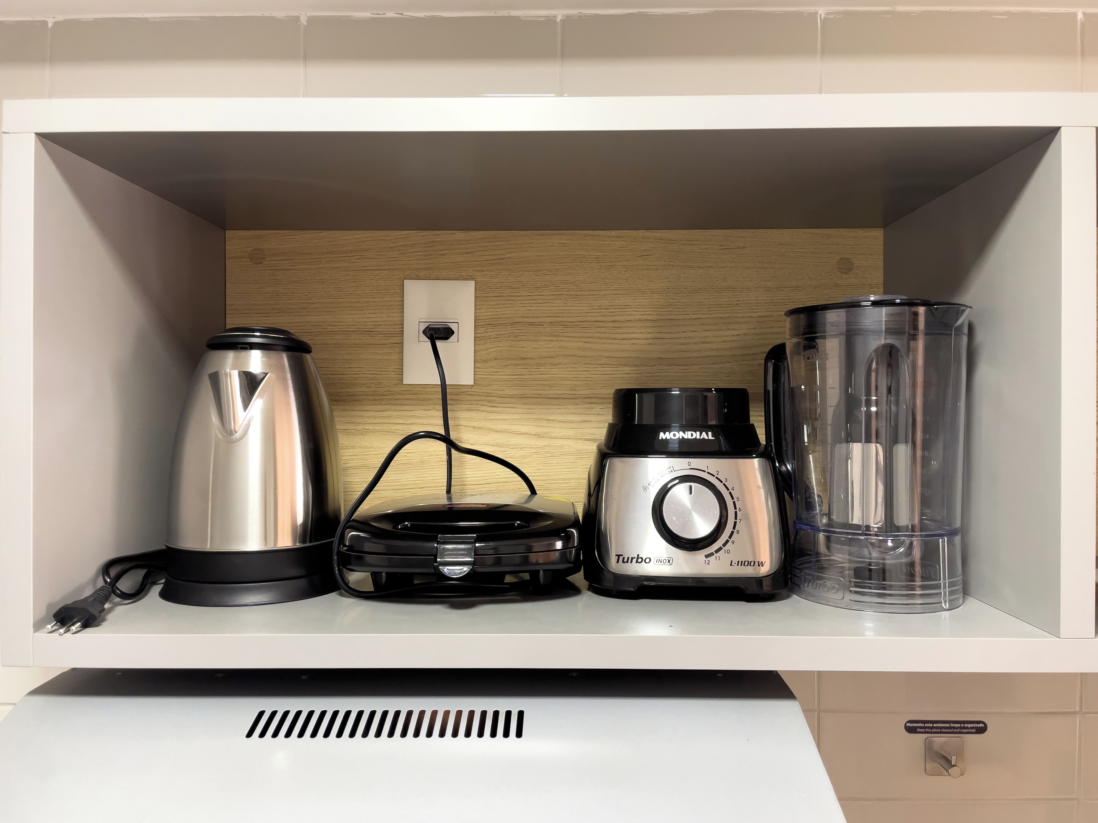 A kitchen with a coffee maker, a blender, and a glass container on the counter.