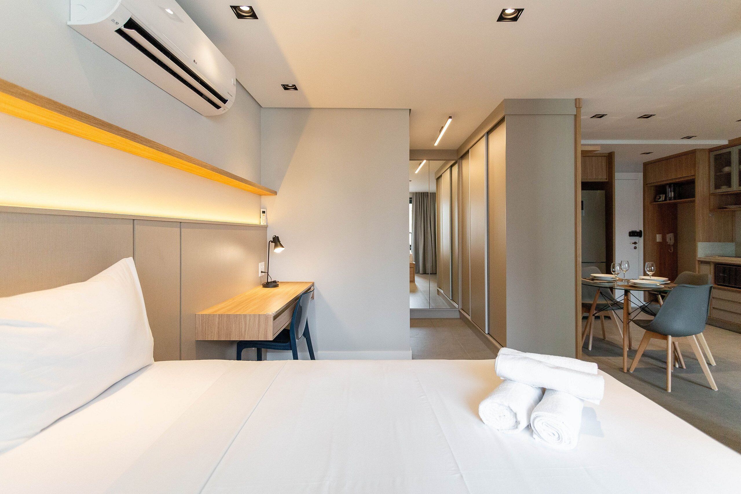 Ein modernes Hotelzimmer mit einem ordentlich bezogenen Bett, einem Schreibtisch mit Stuhl und einem Essbereich mit Tisch und Stühlen.