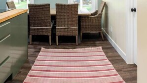 Une cuisine avec une table et des chaises, un tapis à rayures et une fenêtre donnant sur l’extérieur.