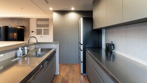 A modern kitchen with stainless steel appliances, a built-in oven, and a coffee maker on the counter. - RIVIERA Kujukuri (Kujukuri)