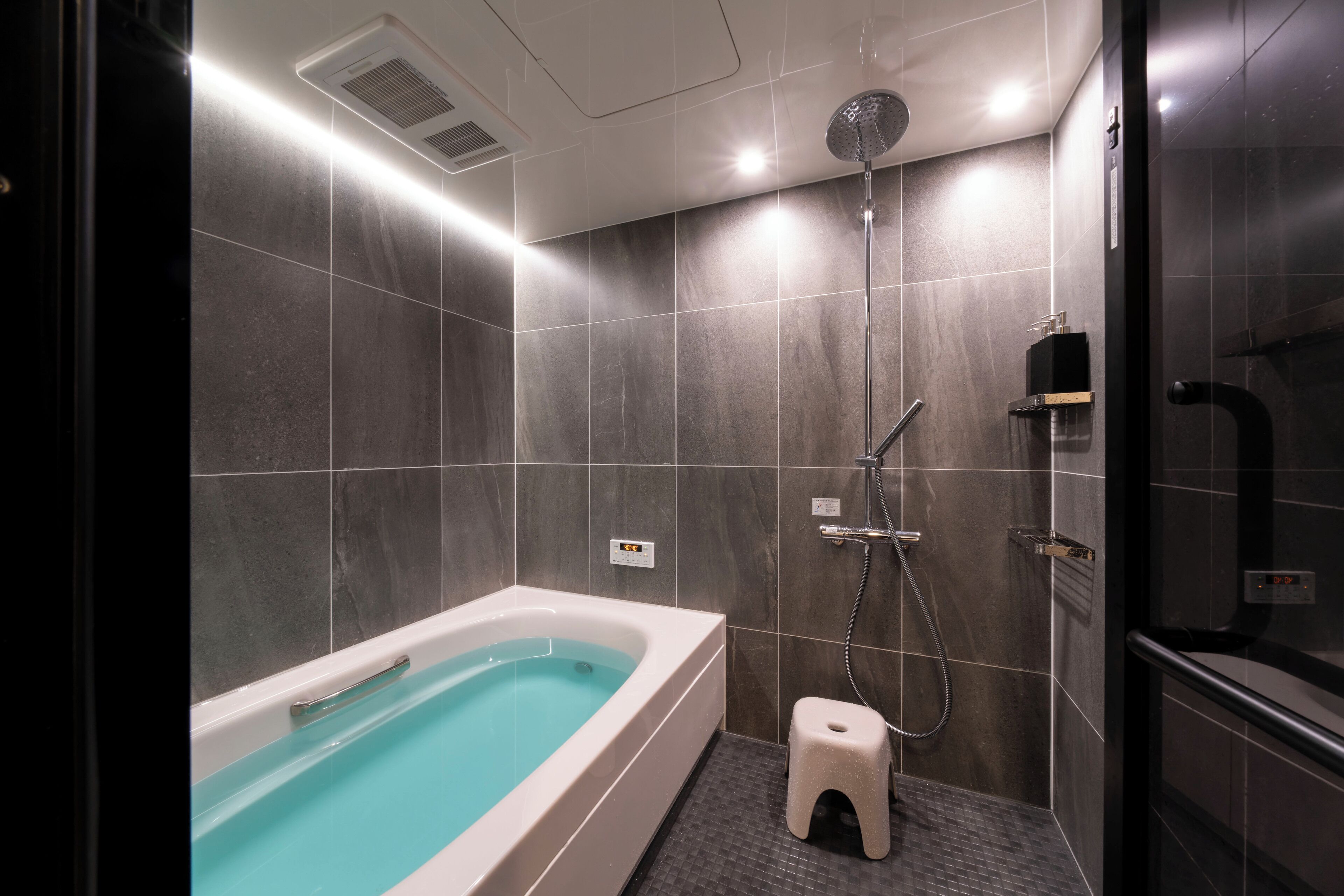 A modern bathroom with a bathtub, shower, and a small stool.