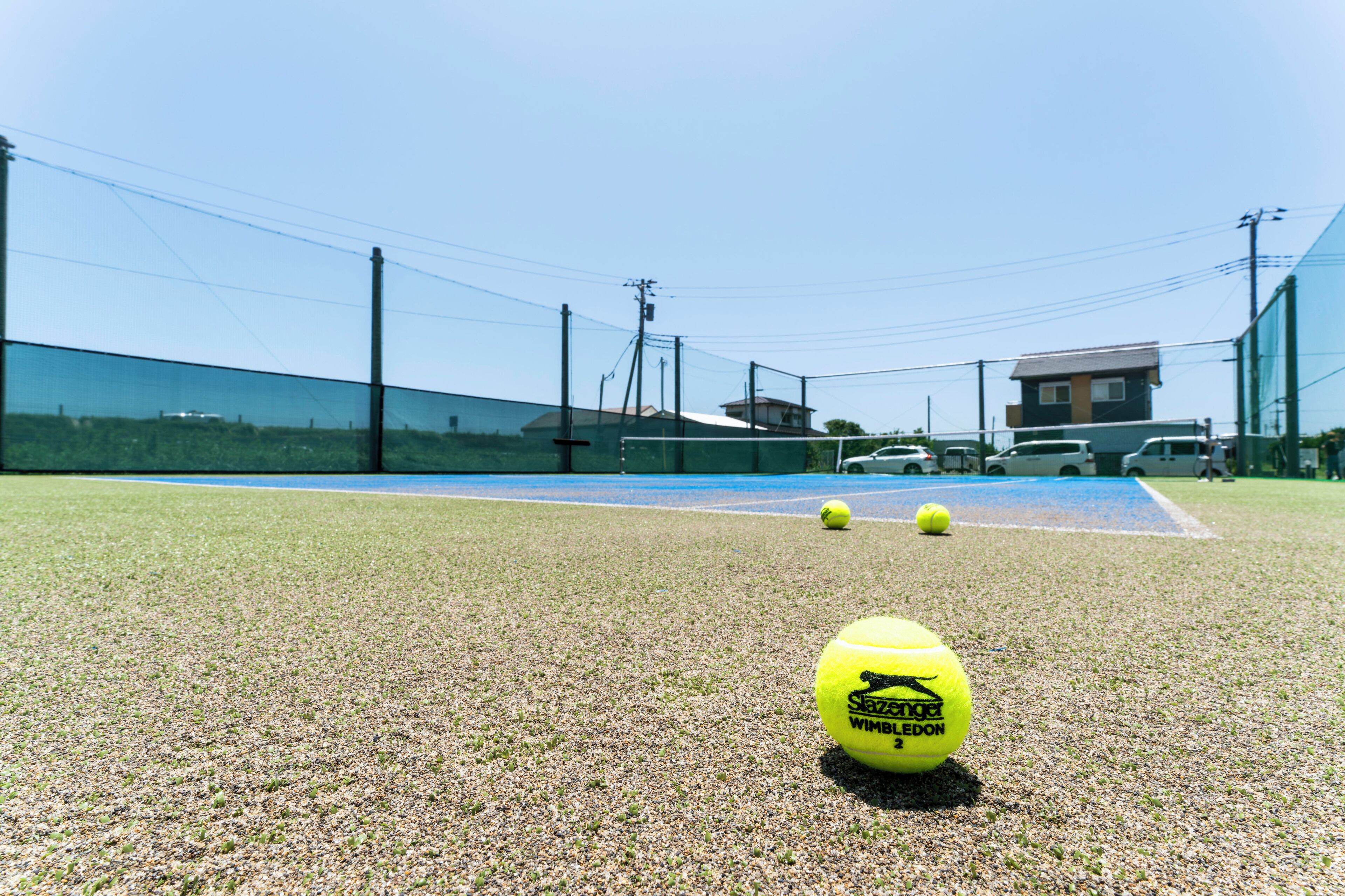 Een tennisbaan met net, tennisballen en een hek.