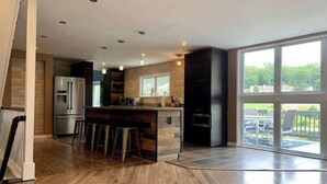 Uma cozinha moderna com ilha central, eletrodomésticos de aço inoxidável e uma grande porta de vidro deslizante que dá para um pátio externo.